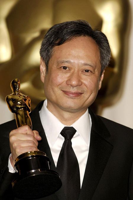 Ang Lee holding up his Oscars on stage.